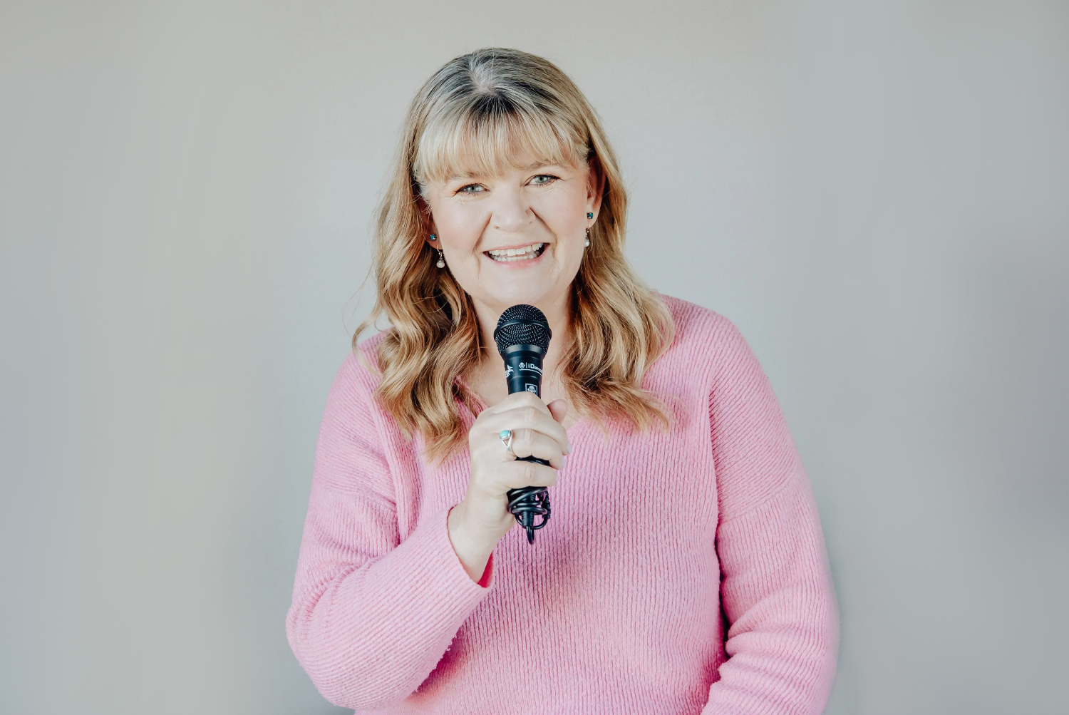 Woman in a pink jersey smiling and holding a mic