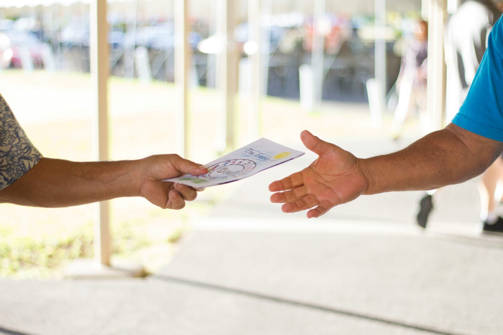 Two arms: one handing a document to the other person