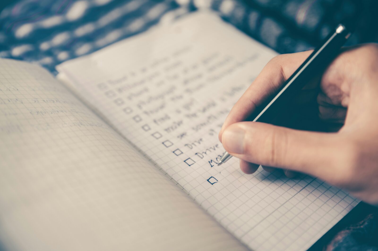 A hand writes a checklist on grid-paper