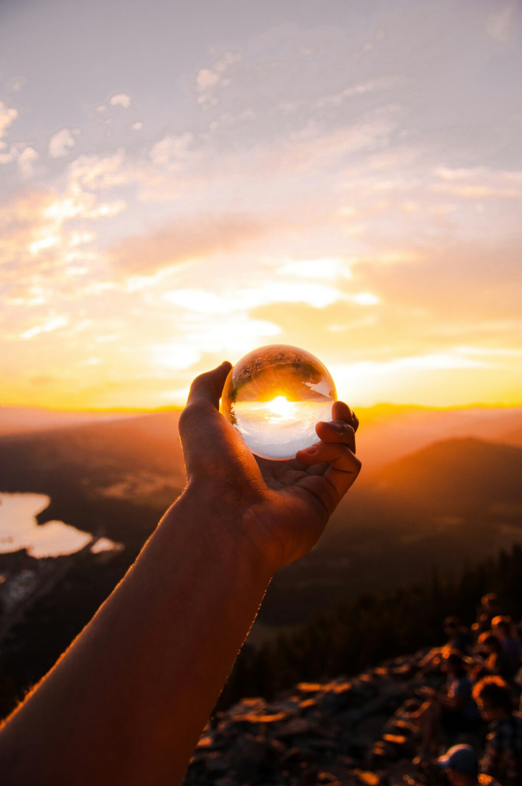 A hand holds a crystal ball towards a sunrise