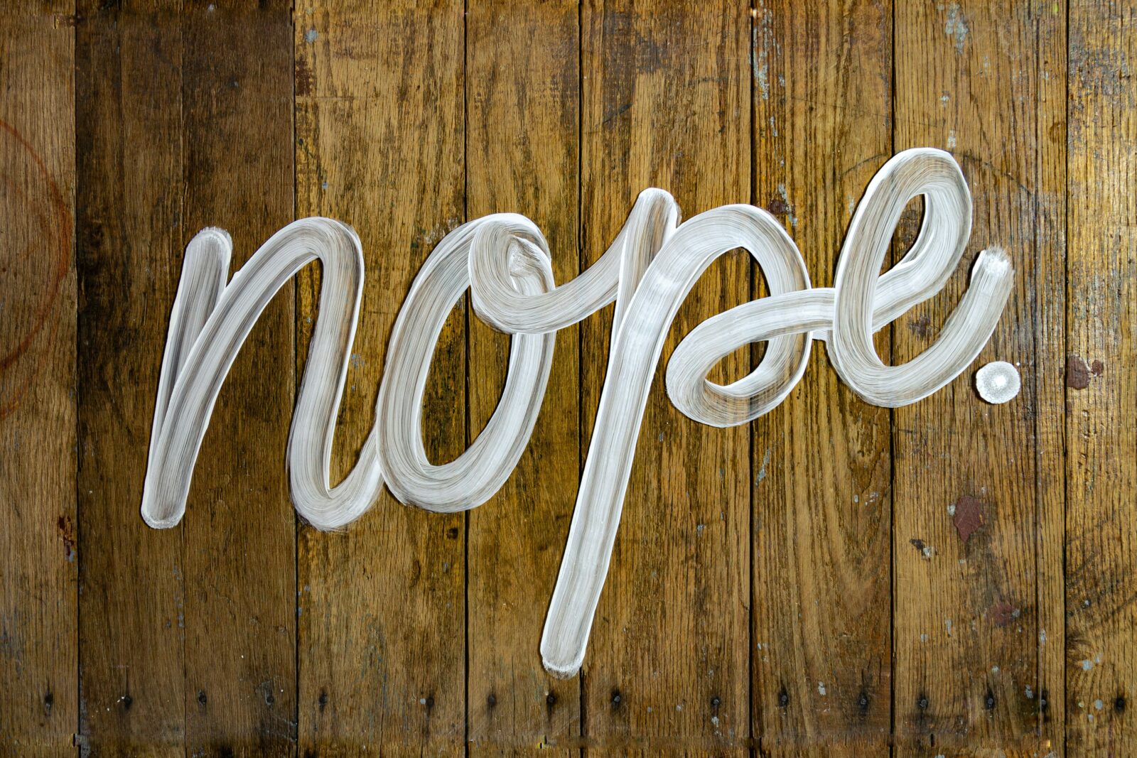 The word ‘nope’ in white paint on a wooden surface.