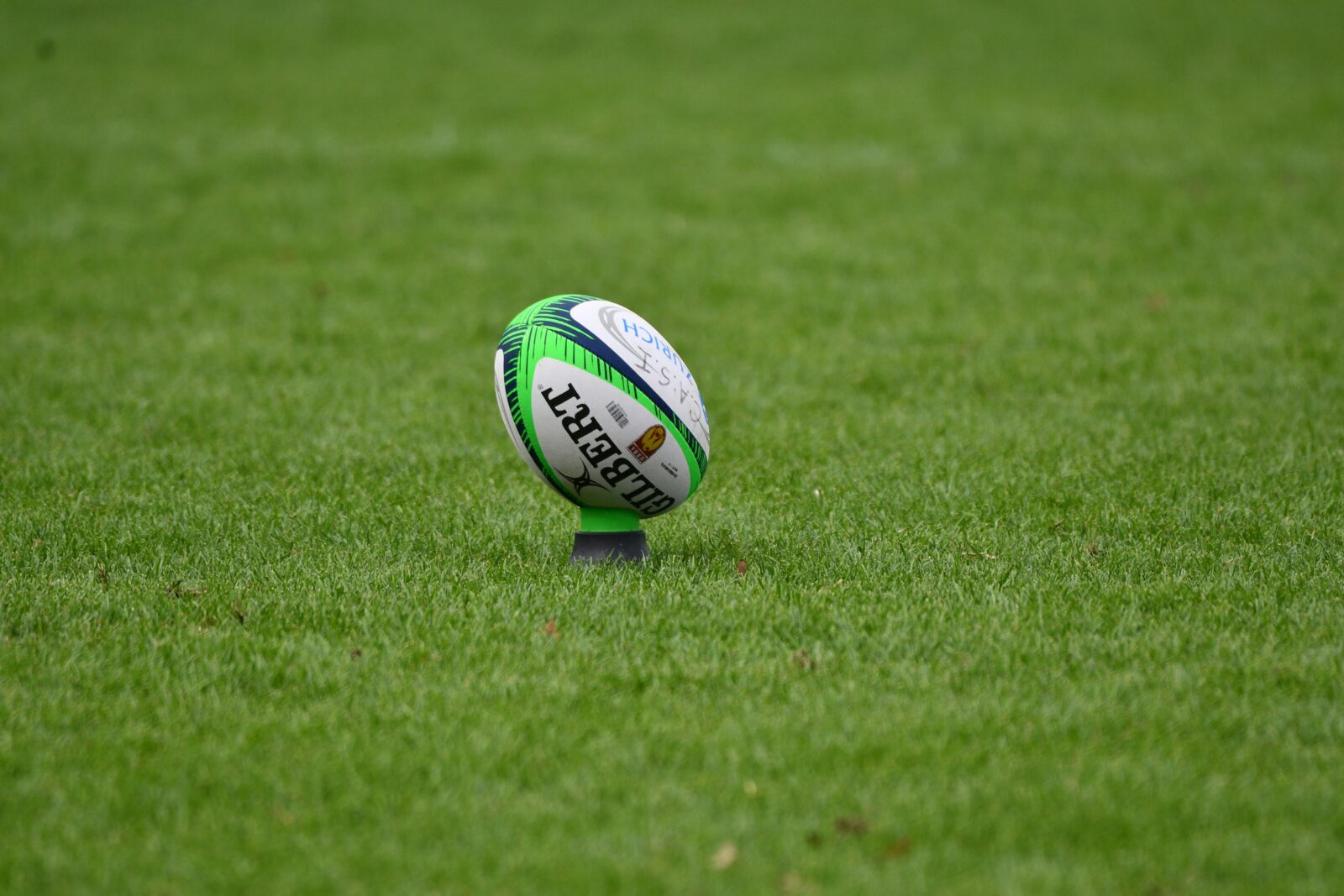 A rugby ball on a tee on a green field