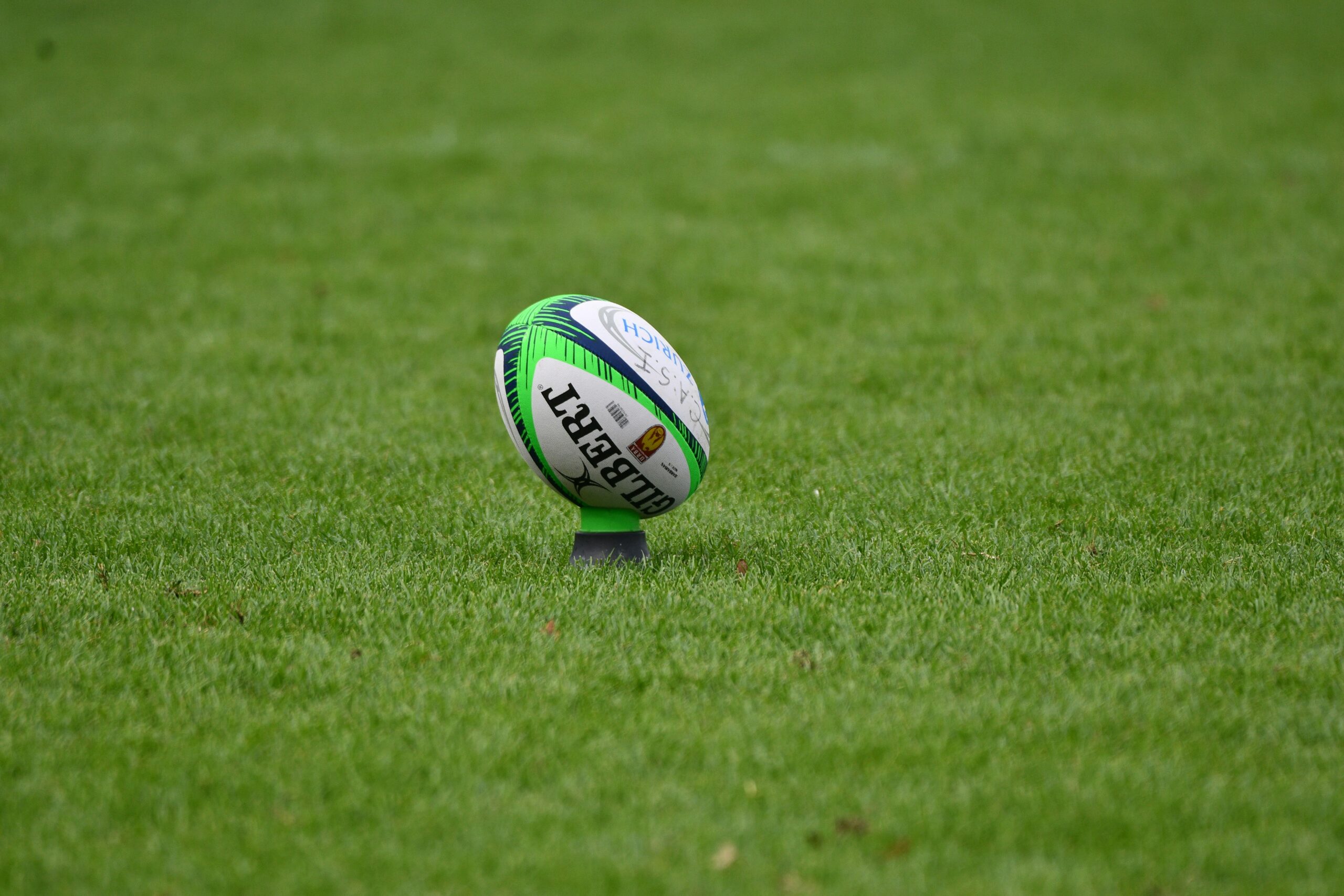 A rugby ball on a tee on a green field